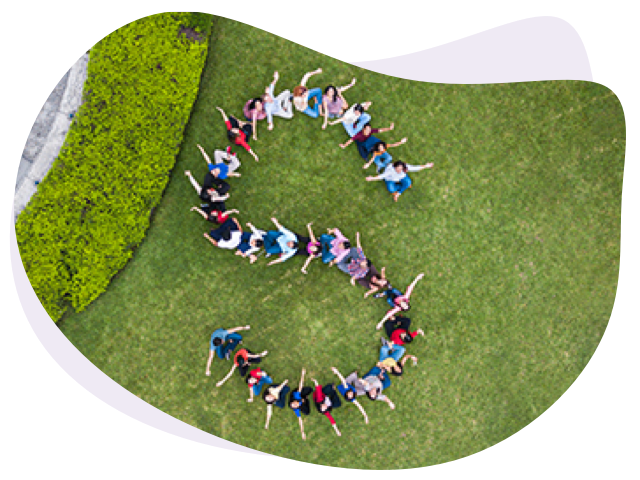 Aerial view of a group of people forming a letter S on a grassy lawn