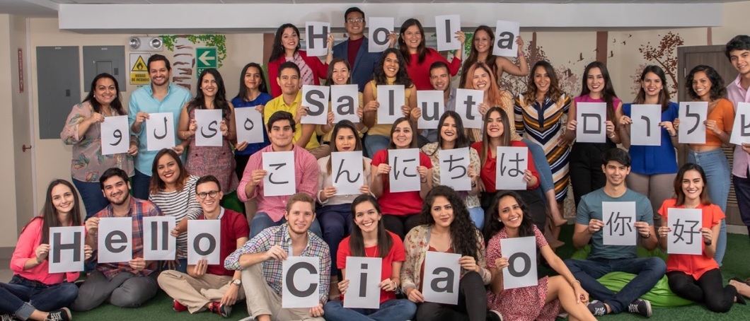 A large group of people holding up letter that spell hello in 8 languages