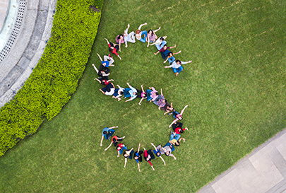 Aerial view of a group of people forming a letter S on a grassy lawn