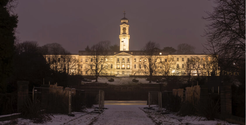 University of Nottingham white building with a clock tower in the evening with snow on the ground