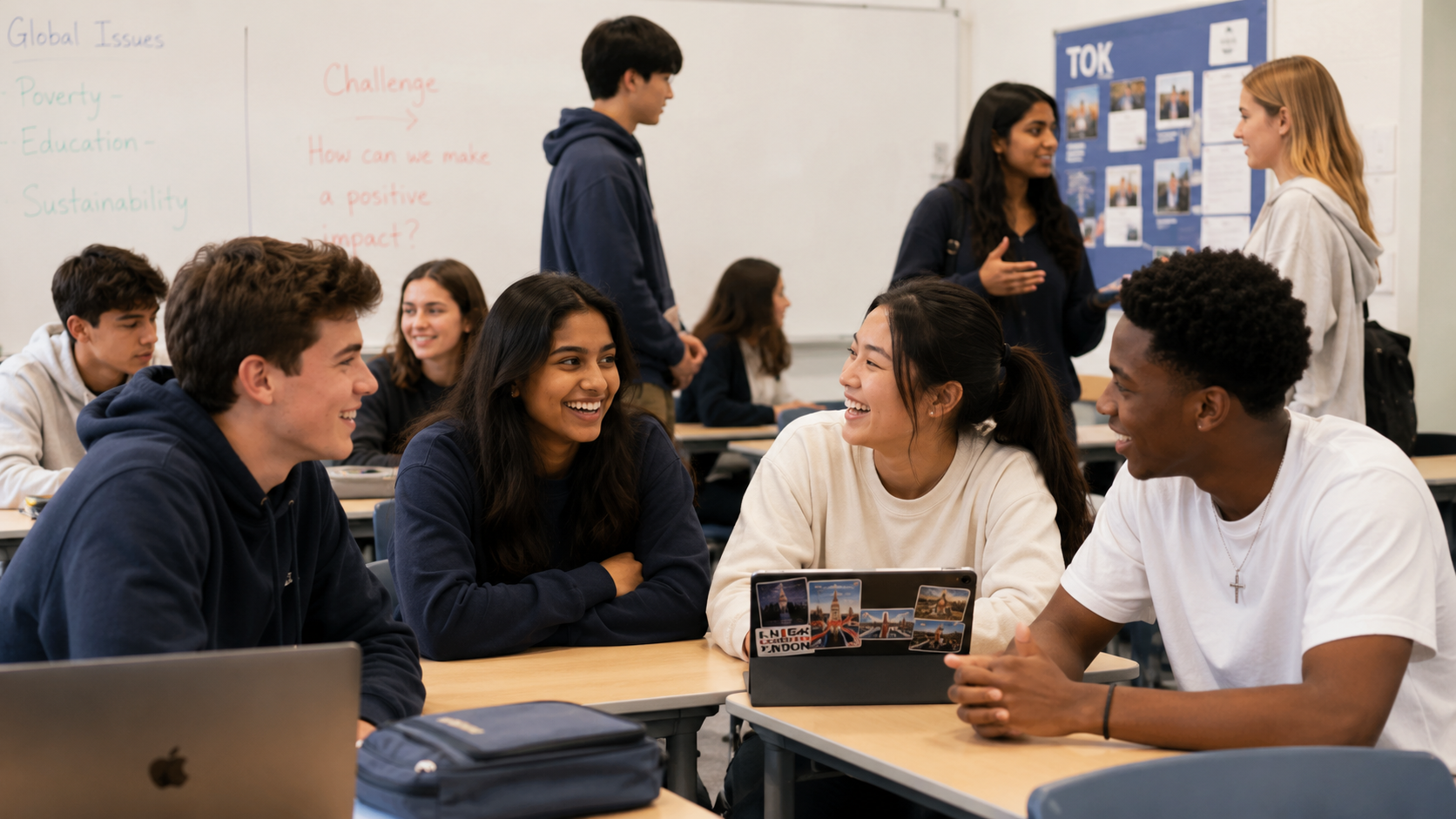 Students smiling and talking in small groups in a classroom.