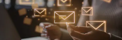 A person sits at a laptop, surrounded by floating digital email icons. The atmosphere is dimly lit, emphasizing the glow of the icons.