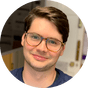 Man smiling with brown hair and glasses